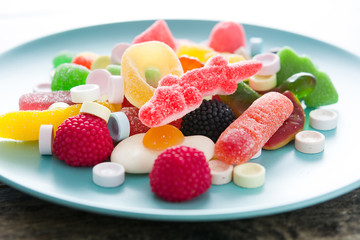 Colorful childs sweets and treats in plate on wooden table