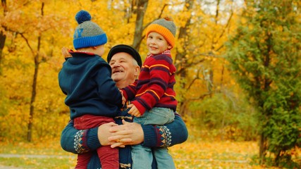 Grandfather and his grandsons in the autumn park