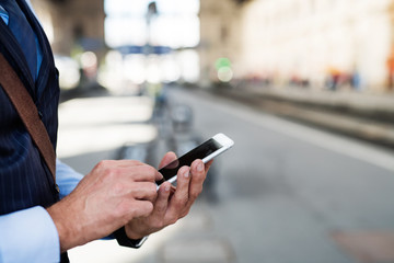Mature businessman with a smartphone in a city.