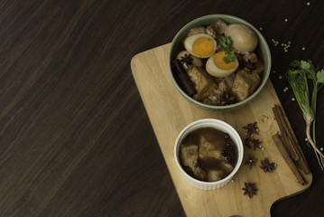 Stewed eggs in a bowl and putting green on a wooden tray. Within half an egg red. Coriander spices and set aside. On black background.