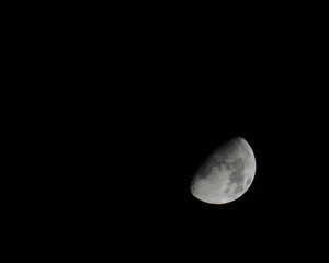 tilted half moon in a dark sky with shadows on craters