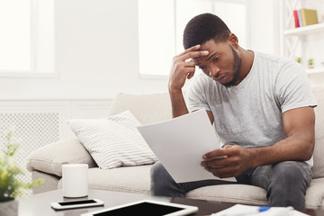 Young tired african-american student reading at home