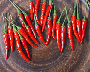 Red hot chili peppers on brown clay flat plate. Copy space. Top view. Background for kitchen. Hot chilli. Homemade clay potter dish.