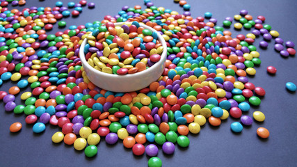 candy colorful confetti on white bowl scattered on black background