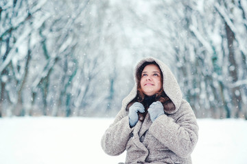 Fototapeta na wymiar Portrait of happy young woman in a snowing winter day, in a park.
