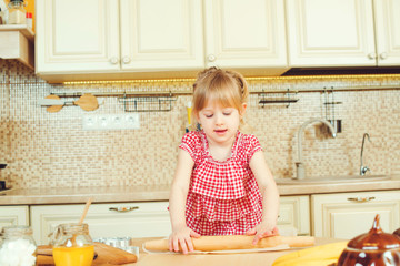 Cute little girl helping her mother bake cookies in a kitchen.