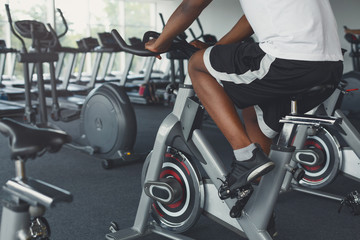 Fototapeta na wymiar Man's legs on exercise bike in fitness club, healthy lifestyle