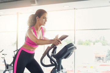 Fototapeta premium Young woman on elliptical trainer