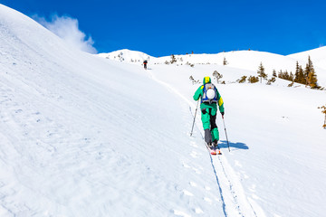 Fototapeta na wymiar A skier is climbing the mountain ridge.