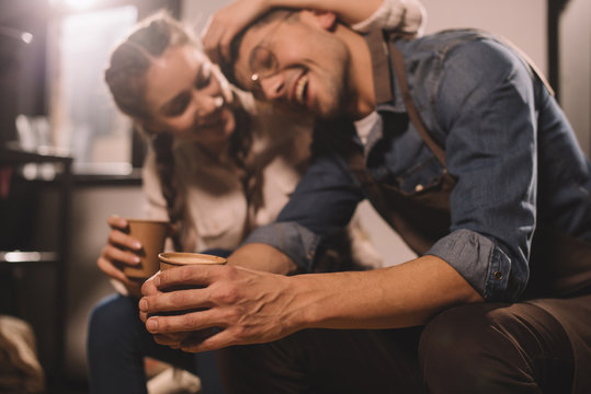 selective focus of couple with cups of coffee having break during work at coffee shop