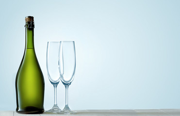 Glasses with champagne and bottle over sparkling holiday background