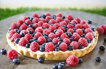 raspberry tart cake on wood and grass