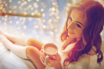 happy woman with cup of cocoa in bed at home