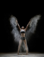 Obraz na płótnie Canvas Girl in top and shorts in a white dust cloud shot