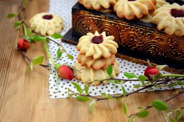 Obraz na płótnie Canvas Shortbread cookies with jam on a cloth surrounded by branches and roses