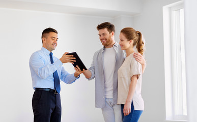 couple and realtor with tablet pc at new home