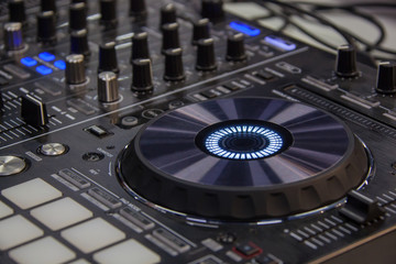 Close-up of backlighted turntable and buttons on DJ mixer console