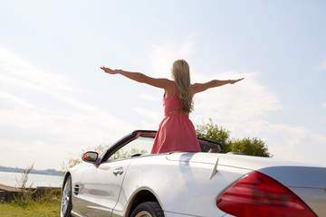 happy young woman in convertible car at seaside