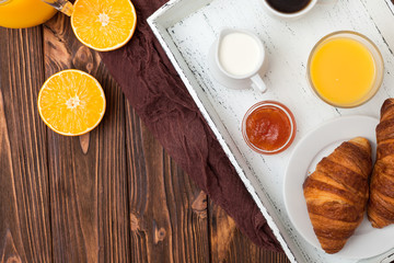 Freshly baked croissant, orange juice, fresh fruits, jam on brown wooden background. French breakfast. Fresh pastries for morning. Delicious dessert. Top view. Closeup photography. Horizontal banner