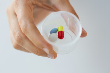 close up of female hand with pills in medicine cup