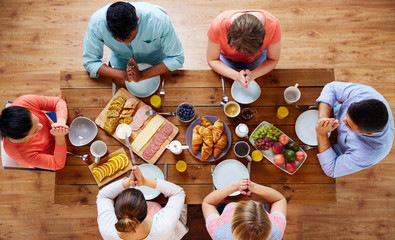 group of people at table praying before meal