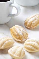 Madeleines and coffee cups on the marble surface.