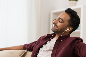 Fototapeta premium happy man in earphones listening to music at home