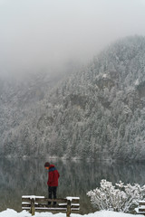 Young man sitting on a lake in Austria in the winter