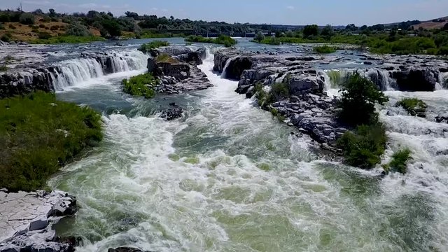 Aerial slow motion of a fast moving river with waterfalls