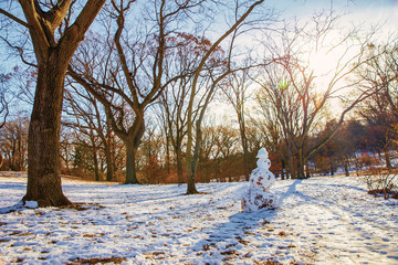 snowman in a spring park. sunny day in the snow-covered forest
