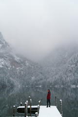 Young man standing on a bridge at a lake in Austria in the winter