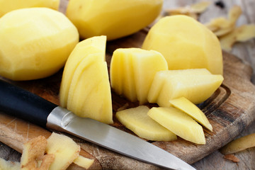 Raw peeled potatoes with a knife