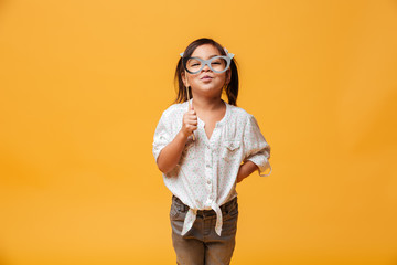 Funny little girl child holding fake glasses.