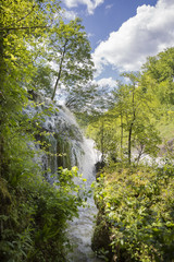 Croatian village of Rastoke by a river canyon with wooden houses in a green lanscape with trees and a waterfall, Croatia