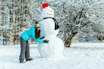 woman making snowman in winter day