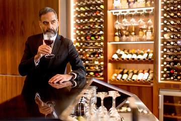 Handsome mature man tasting red wine