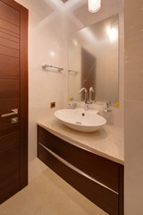 A bedside table with a white sink and a square mirror