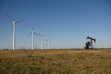 Wind energy turbines and crude oil pump jack pumping oil in West Texas, USA