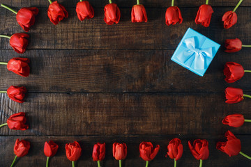 Blue gift box with red tulips wooden background copy space