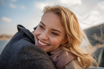 Long-awaited meeting. Close up portrait of young woman in arms of boyfriend while smiling and...
