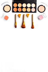 Decorative cosmetics pattern. Eyeshadows, rouge, brushes on white background top view copyspace