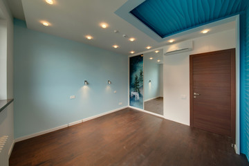 The room with a blue wall and the built-in sliding wardrobe, with a wooden brown door