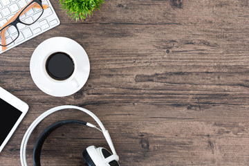 Brown wood office desk table and equipment for working and listening music with white headphone in top view and copy space.
