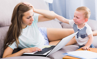 Perplexed woman is having problems with work while child crying