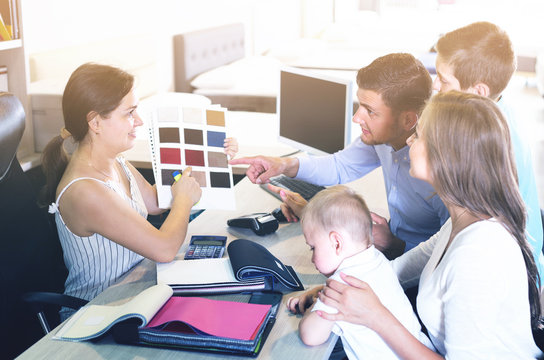 Smiling Saleswoman Is Showing To Young Family The Patterns Of Ma