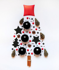 Christmas tree from small objects: stars, Christmas decorations, anise, cinnamon, cloves, cones, red candies, red pillow. On a white background. Top view. christmas, new year