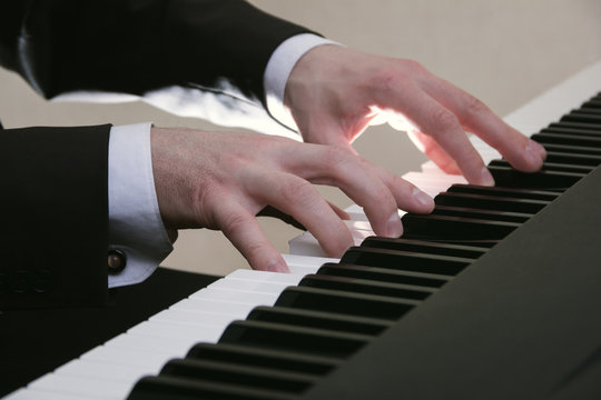 man's hands playing on a piano at the concert