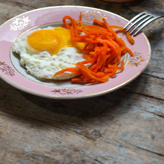 fried eggs with carrots - serving on a wooden table