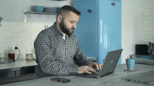 Man working on laptop by the table at home
