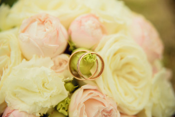 Big nice wedding bouquet in woman's hands. The bride puts the ring on the groom's finger.